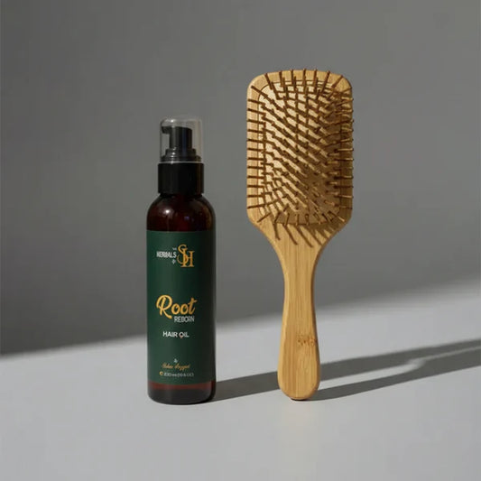 Root Reborn organic hair oil by Herbals by SH next to a wooden paddle brush.