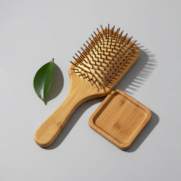 Eco friendly wooden hair brush alongside a green leaf by Herbals by SH.